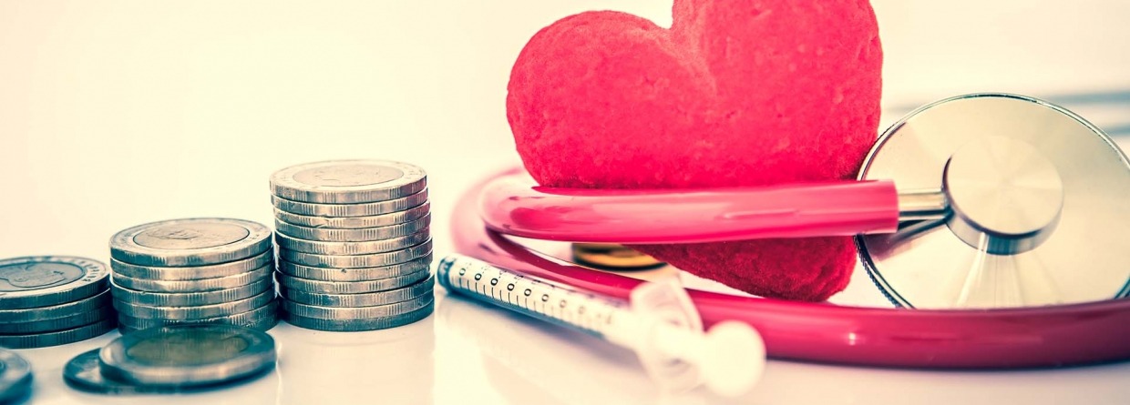Medisch hart met stethoscoop en injectiespuit en stapels munten