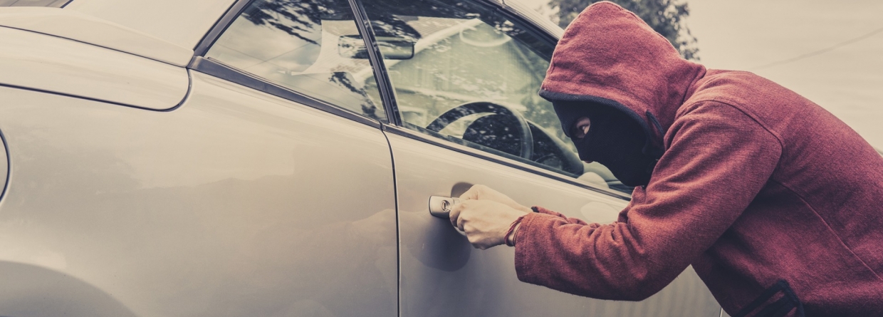 een dief die wil inbreken in een auto