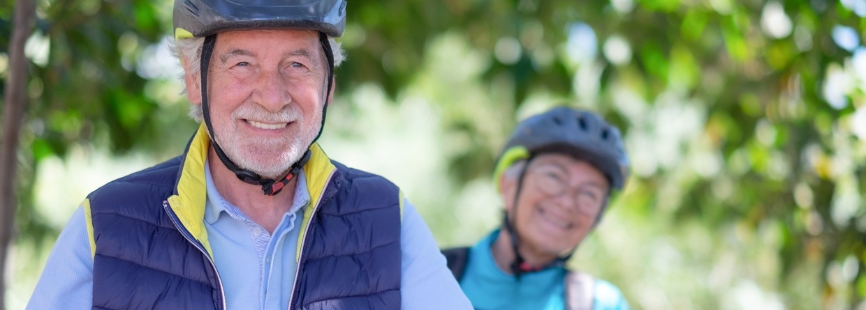 Senioren man en vrouw op de fiets met een fietshelm op