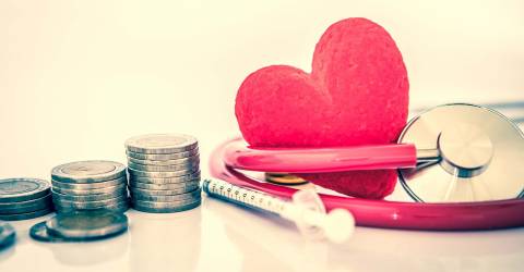 Medisch hart met stethoscoop en injectiespuit en stapels munten