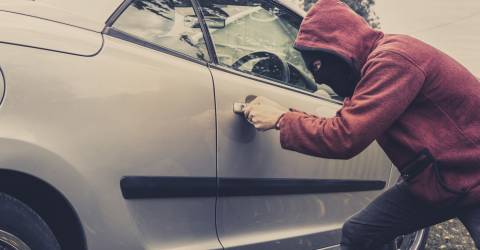 een dief die wil inbreken in een auto