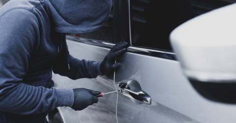 autodief is auto aan het open breken met een schroevendraaier