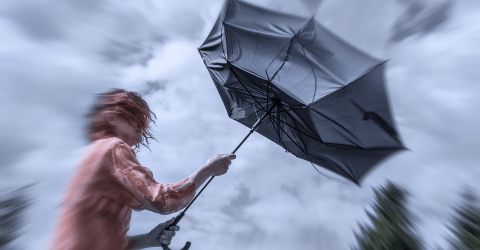 Vrouw met rood haar houdt een paraplu vast in de storm